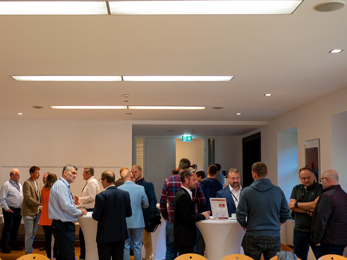 Participants talking at standing tables in the Hofsaal of Schloss Puchberg