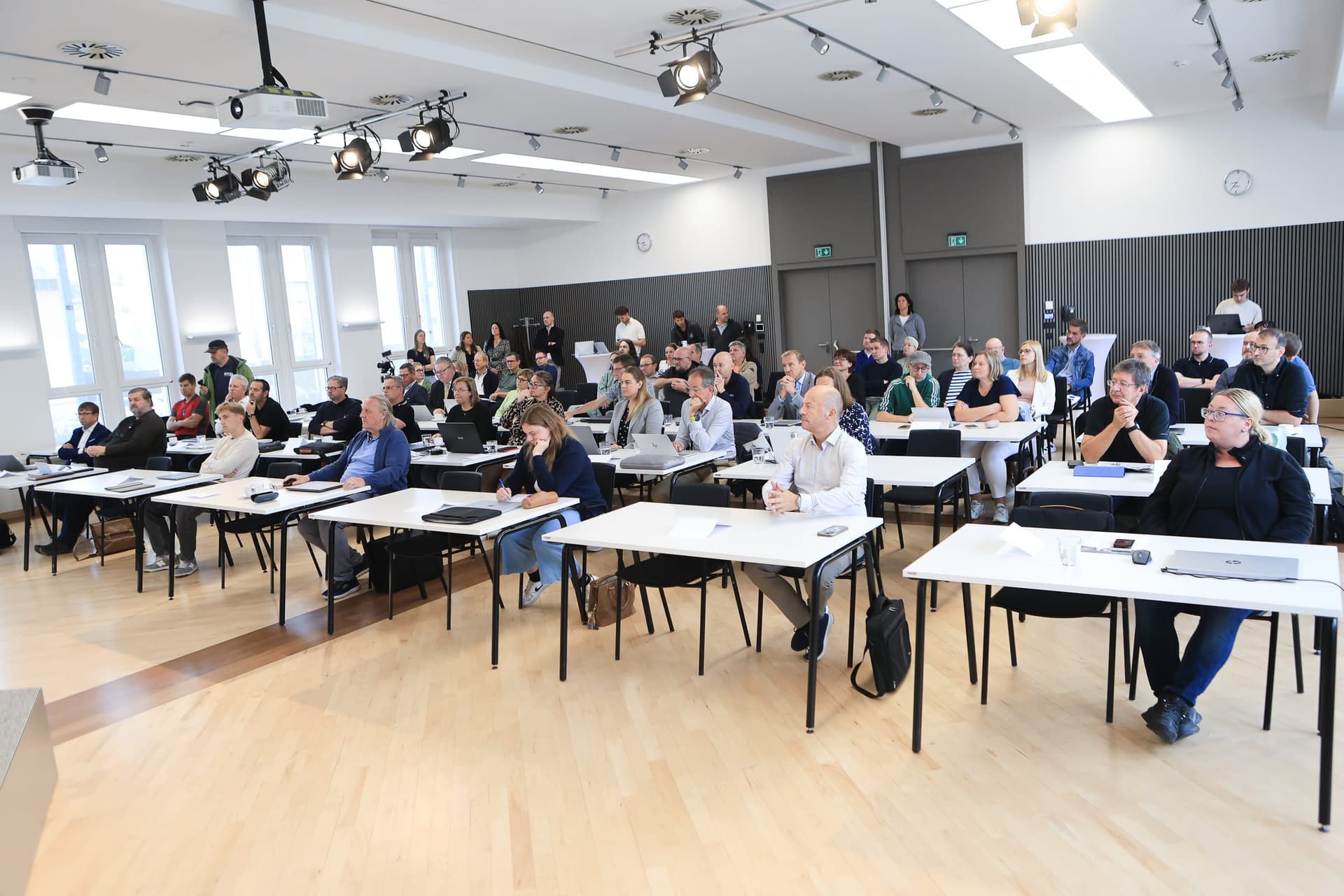 Rows of participants at white tables with laptops in the bright hall of WKO Grieskirchen