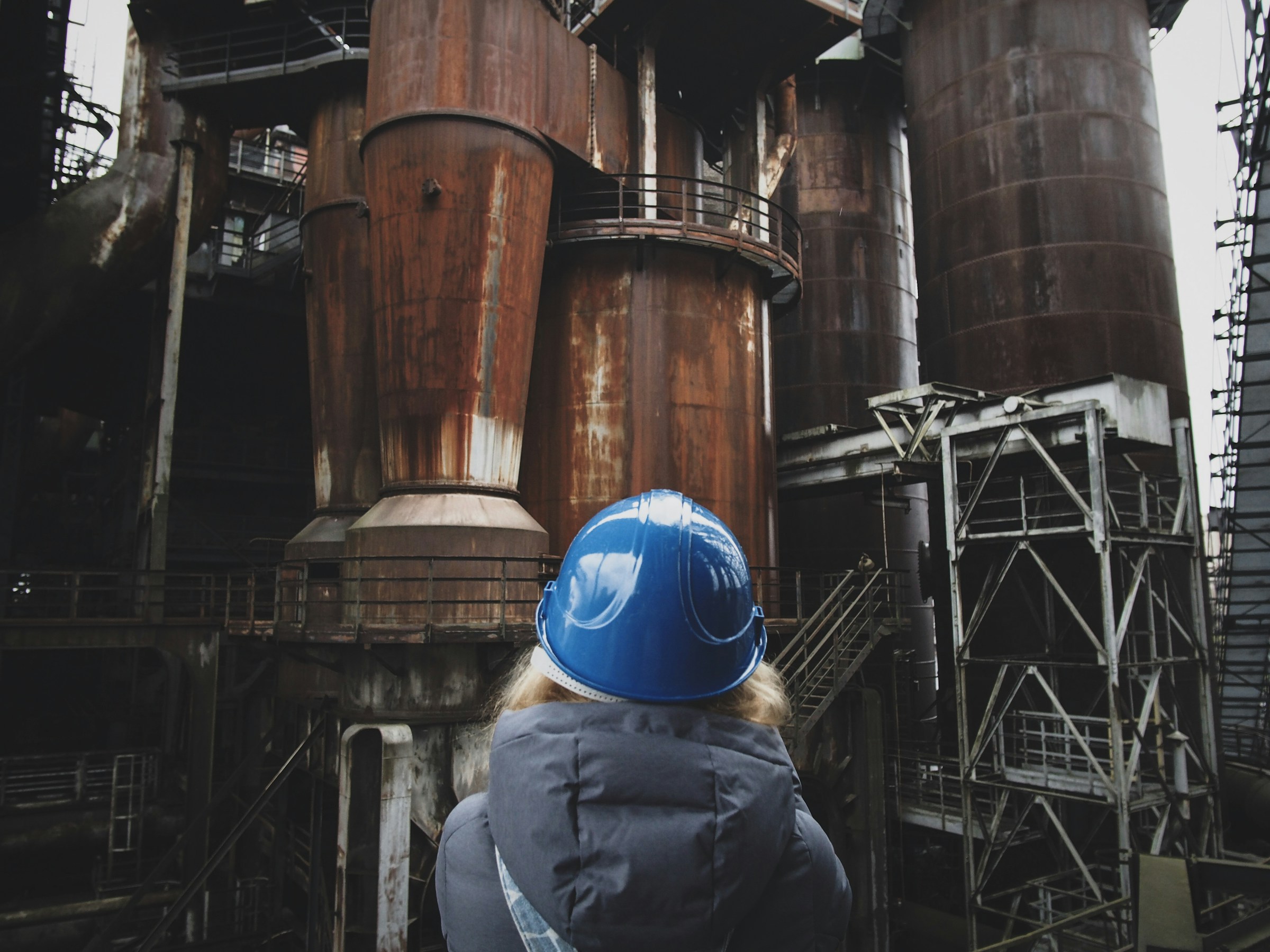 Engineer in a blue hard hat looking up at the process towers of a heavy industrial plant