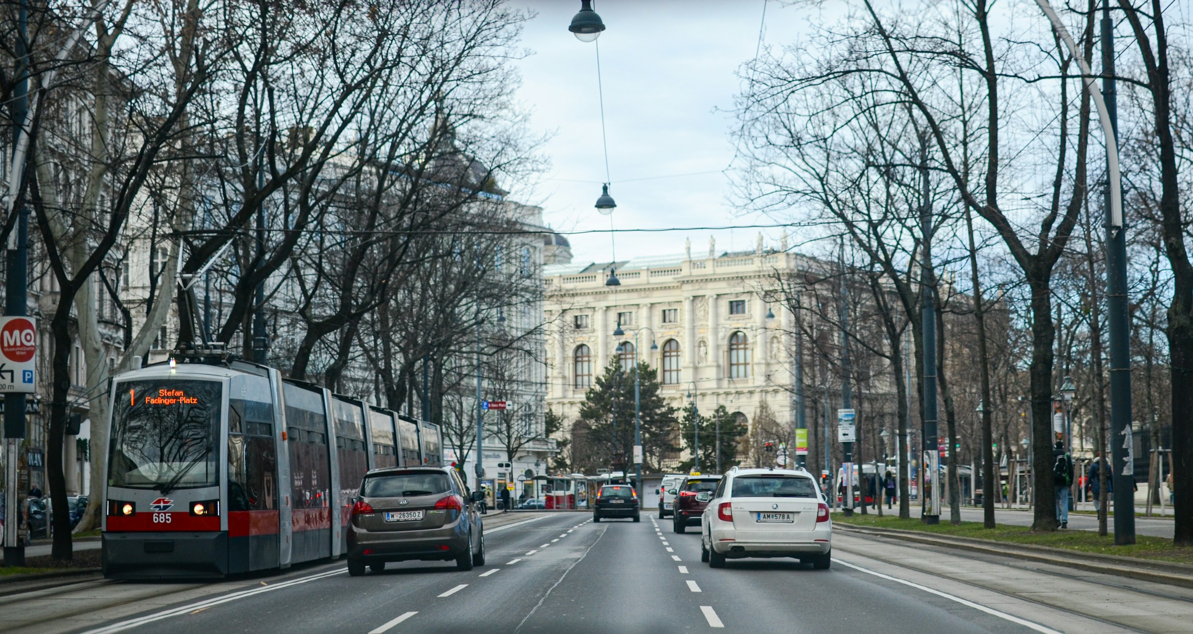 Vienna Ringstrasse with a red tram passing historic buildings under bare winter trees